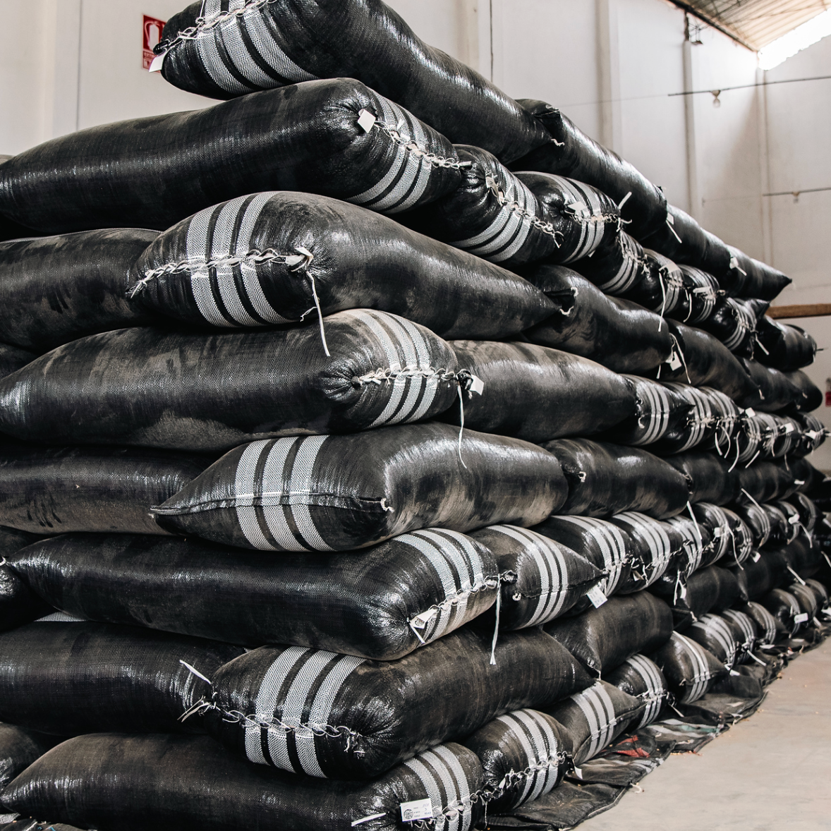Stacks of black bags with white stripes in a warehouse setting